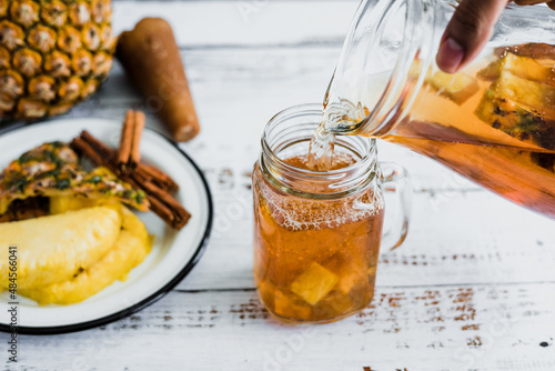 Tepache mexican Fermented pineapple drink and hand holding a Jar with kombucha homemade probiotic superfood sliced pineapple beverage in Mexico city	 photo