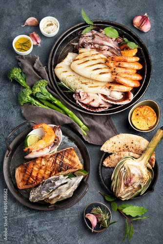 Grilled fish and seafood assortment on dark background.