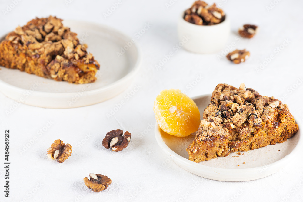 Pieces of homemade tangerine pie with nuts in plates on a light table. Healthy food, sugar, gluten and lactose free, vegan. Pieces of homemade tangerine pie with nuts in plates on a light table. Healthy food, sugar, gluten and lactose free, vegan.