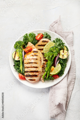 Grilled chicken with vegetables on light background.
