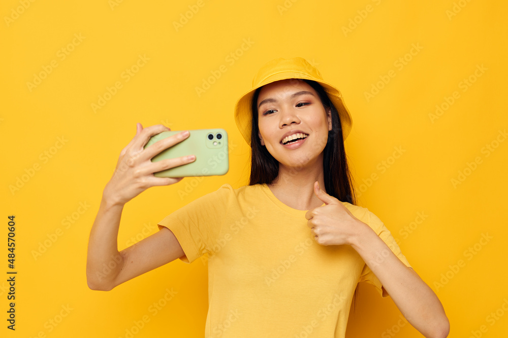 woman holding a phone posing lifestyle technology yellow background unaltered woman holding a phone posing lifestyle technology yellow background unaltered