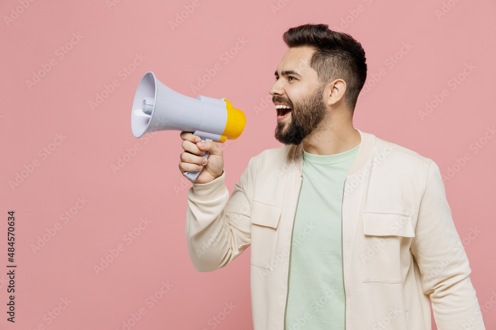 Young happy man 20s wearing trendy jacket shirt hold shout aside scream in megaphone announces discounts sale Hurry up isolated on plain pastel light pink background studio. People lifestyle concept. Young happy man 20s wearing trendy jacket shirt hold shout aside scream in megaphone announces discounts sale Hurry up isolated on plain pastel light pink background studio. People lifestyle concept.