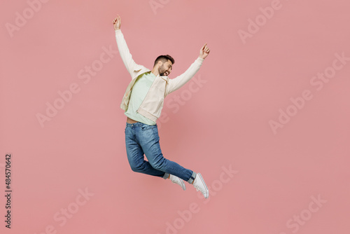 Full size young overjoyed exultant jubilant happy fun man 20s in trendy jacket shirt jump high with outstretched hands isolated on plain pastel light pink background studio. People lifestyle concept.