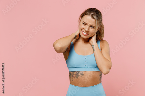 Young sad strong sporty athletic fitness trainer instructor woman in blue tracksuit spend time in home gym hold hands behind neck isolated on pastel plain light pink background Workout sport concept © ViDi Studio