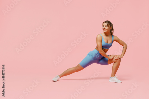 Fototapeta Naklejka Na Ścianę i Meble -  Full size young sporty athletic fitness trainer woman wear blue tracksuit spend time in home gym train do stretch legs squat exercise isolated on pastel plain pink background. Workout sport concept.