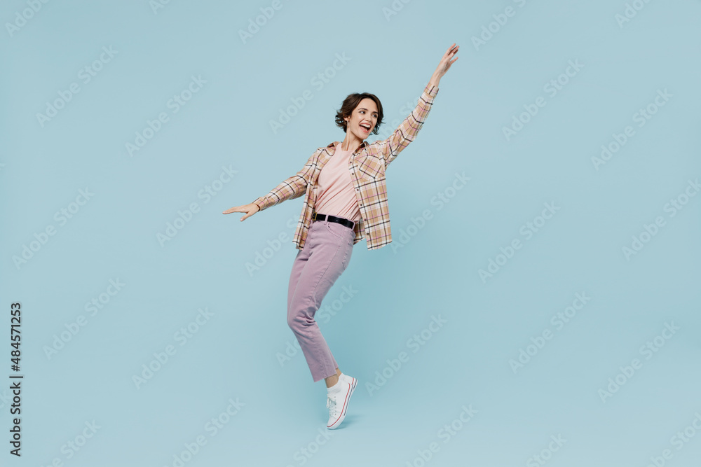 Full body young smiling happy woman 20s wearing casual brown shirt stand on toes dance leaning back fooling around isolated on pastel plain light blue color background studio People lifestyle concept Full body young smiling happy woman 20s wearing casual brown shirt stand on toes dance leaning back fooling around isolated on pastel plain light blue color background studio People lifestyle concept