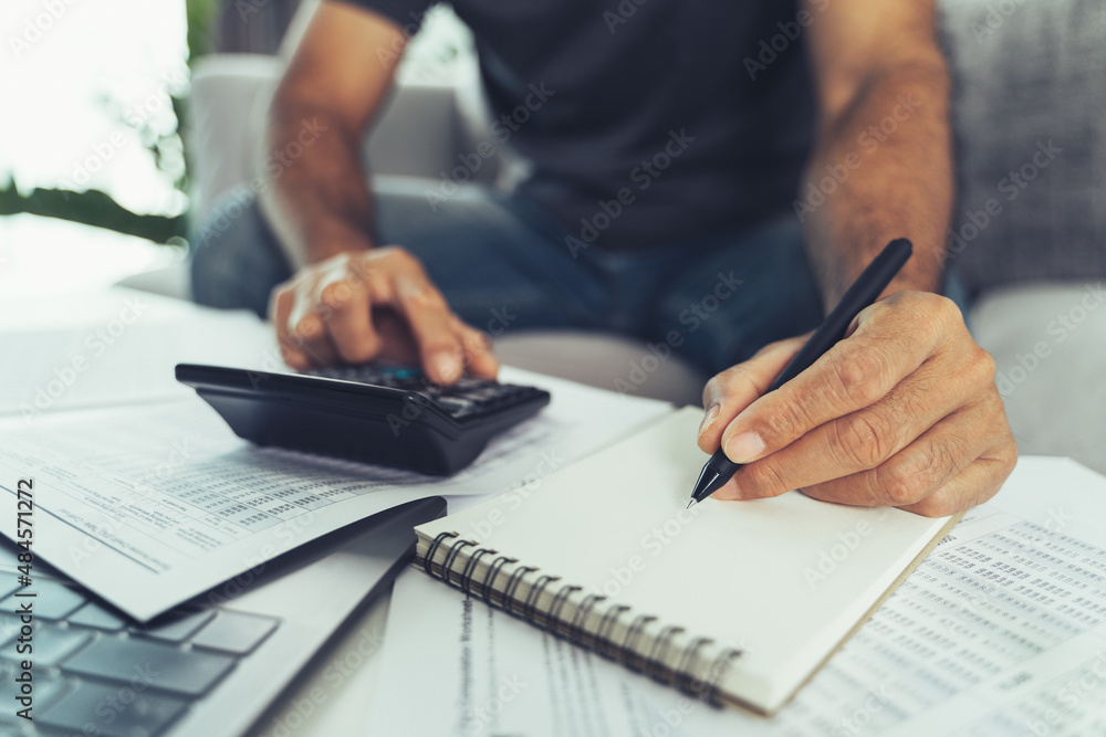 Man is calculating annual tax with calculator and filling form of Individual Income Tax Return. Season to pay Tax and Budget planning concept. Man is calculating annual tax with calculator and filling form of Individual Income Tax Return. Season to pay Tax and Budget planning concept.