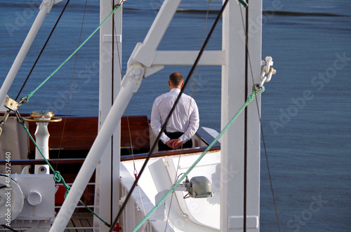 Partial Close up detail view of officer on navigational bridge with superstructure of classic white cruiseship cruise ship liner against blue sky on sunny day photo