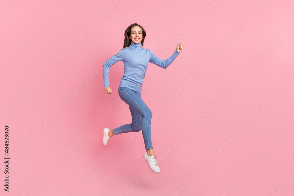 Photo of sporty energetic lady jump run fast hurry wear blue turtleneck jeans shoes isolated pink color background