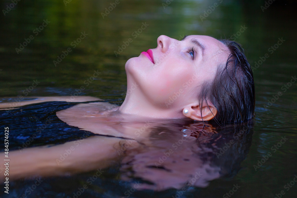 Fototapeta premium mystical woman in black dress splashes in the river