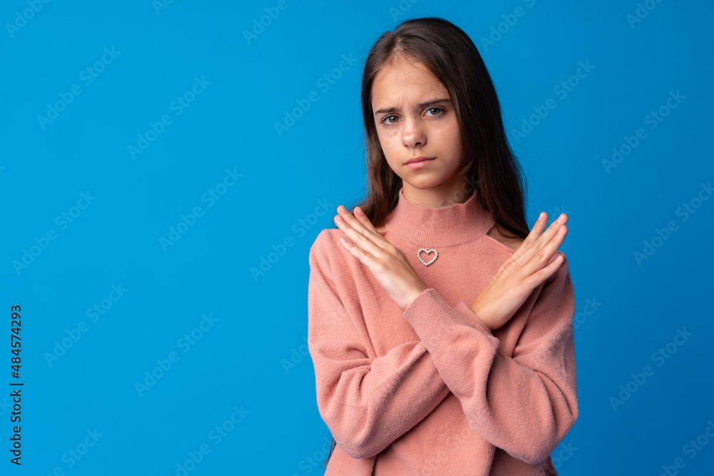 Young beautiful teen girl crossing arms doing negative sign on blue background Young beautiful teen girl crossing arms doing negative sign on blue background