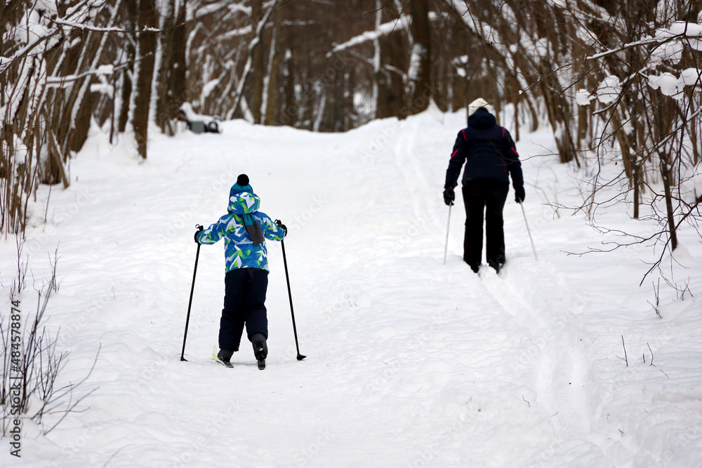 Kid boy and woman skiing in winter park. Family leisure outdoors, skiers on a snow