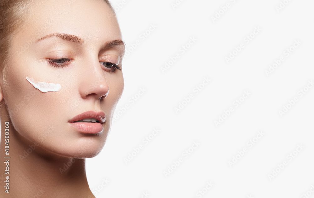 Beautiful young woman with cosmetic cream on a cheek Beautiful young woman with cosmetic cream on a cheek