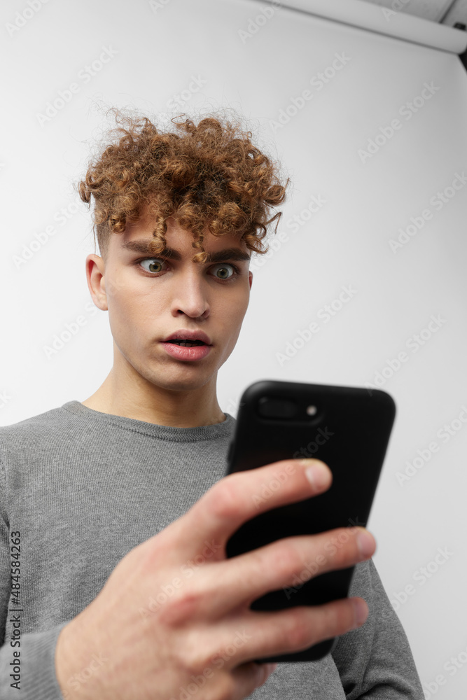Attractive man talking on the phone posing emotions light background Attractive man talking on the phone posing emotions light background