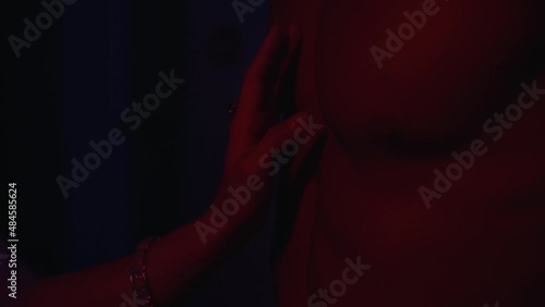 woman touching naked torso of man in neon light