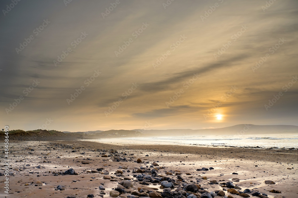 Strandhill beach at sunset. Sligo, Ireland. Big beach with stunning view and powerful ocean waves. Popular for surfing. Calm tranquil atmosphere.