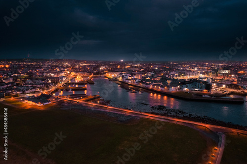 Galway city center illuminated at night. Aerial high point view. Dark scene. Town at night. Popular travel destination. Business and educational center. City lights glow in the dark.