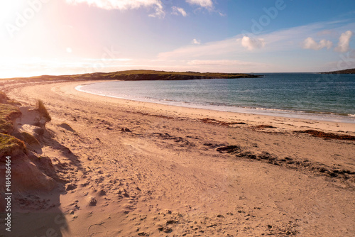 Dog's bay beach at sunset. Sun flare. County Galway, Ireland, Connemara. Popular tourist place known for sand and stunning view and clean blue ocean water. Irish nature scene.