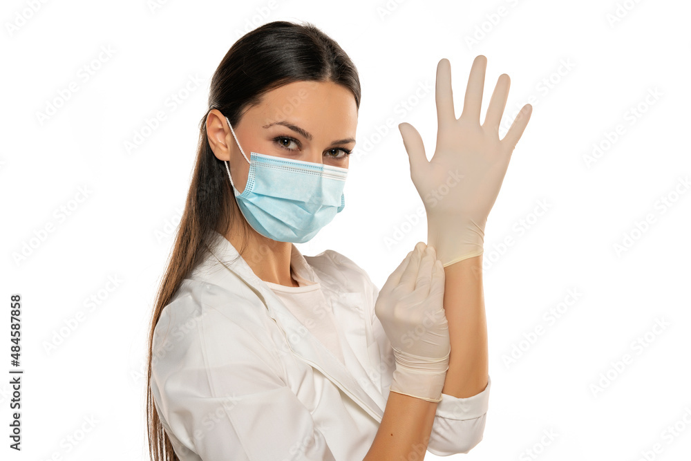Beautiful female doctor or nurse wearing protective mask and latex or rubber gloves on white background with copyspace Beautiful female doctor or nurse wearing protective mask and latex or rubber gloves on white background with copyspace