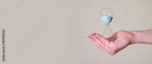 Hourglass in the hands of a man on a light background.