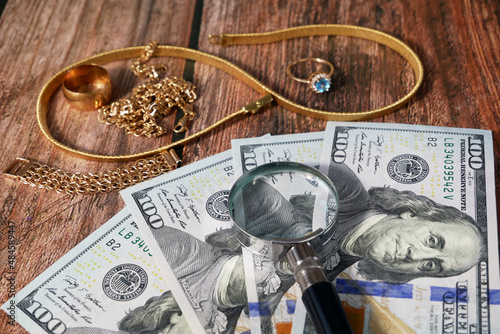 many golden and silver jewelry and cash money фтв magnifying glass on wooden bakground, pawnshop concept, jewelry shop concept