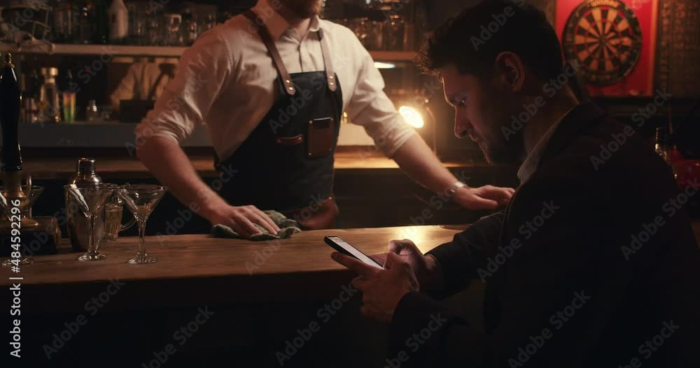 Caucasian male bartender wiping bar after closing for the night Caucasian male bartender wiping bar after closing for the night
