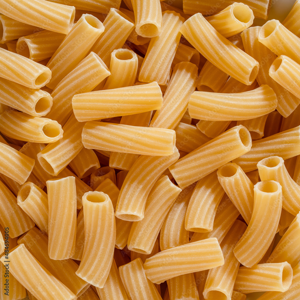 raw pasta rigatoni top view. Macaroni pasta background. Carbo food, mediterranean diet, italian food. Food background. square format raw pasta rigatoni top view. Macaroni pasta background. Carbo food, mediterranean diet, italian food. Food background. square format