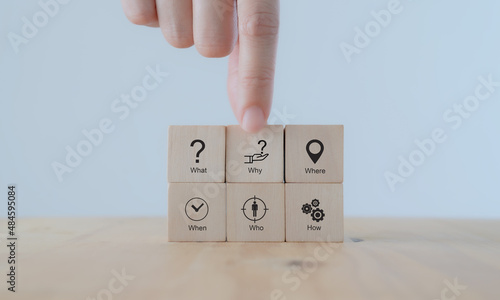 5W1H concept. Business framework and analysis. WHO WHAT WHERE WHEN WHY HOW Questions. The wooden cubes with 5W1H symbols and hand holds 