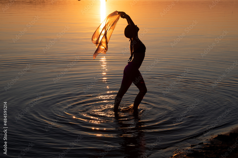 Girl dancing in water. Woman practice Yoga on the beach. Sunset evening