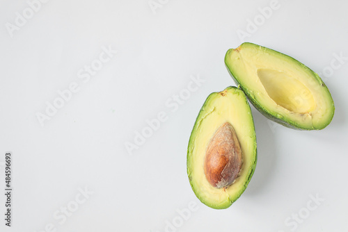 Two halves of avocado isolated on the white background. One slice with core. Women health and vegan concept. Copy space.