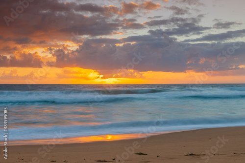 Sunrise at the seaside with waves and clouds