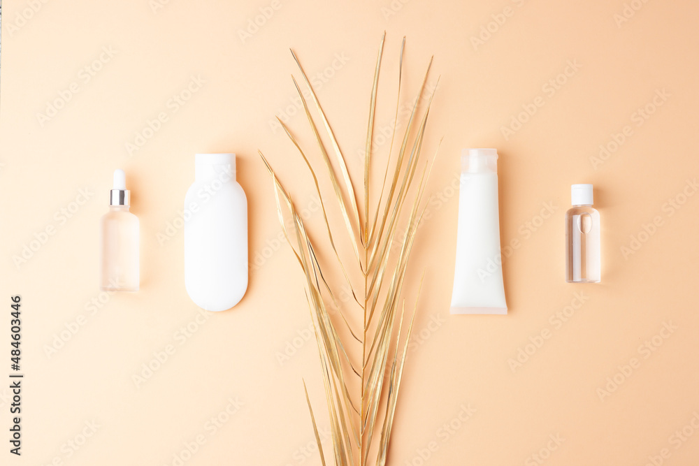Cosmetic skin care products with palm leaf on pastel beige background. Flat lay, copy space