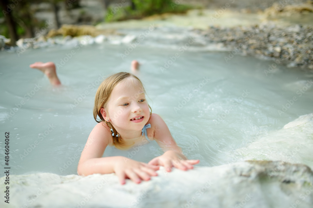 Young girl bathing in Bagni San Filippo, small hot spring containing calcium carbonate deposits, forming white concretions and waterfalls. Geothermal pools and hot springs in Tuscany, Italy. Young girl bathing in Bagni San Filippo, small hot spring containing calcium carbonate deposits, forming white concretions and waterfalls. Geothermal pools and hot springs in Tuscany, Italy.