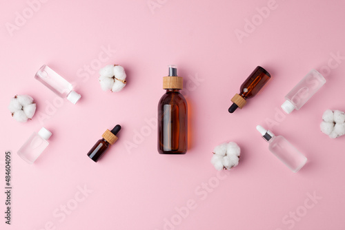 Cosmetic skin care products with flowers on rose background. Flat lay, copy space