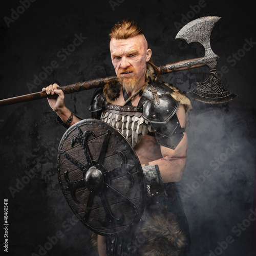 Violent viking with shield and axe posing in smoke