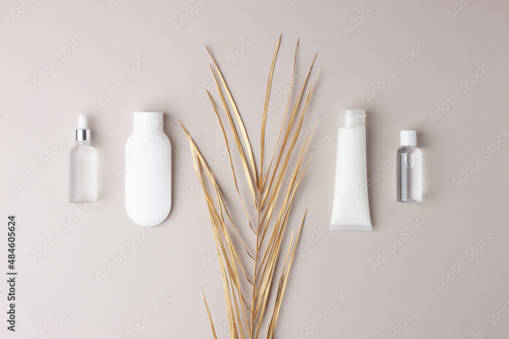 Cosmetic skin care products with palm leaf  on grey background. Flat lay, copy space