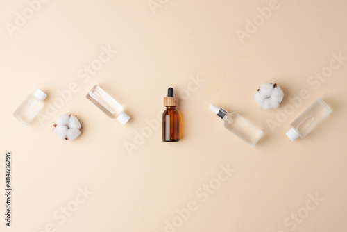 Cosmetic skin care products with flowers on pastel beige background. Flat lay, copy space