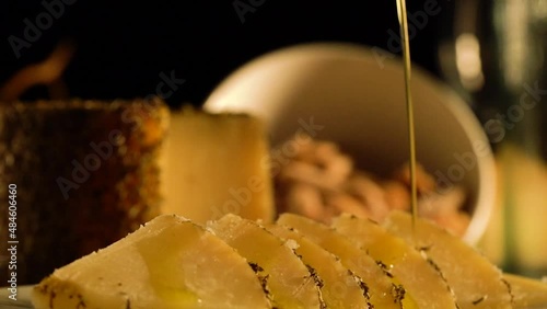 9 second Full HD video clip with shallow depth of field. Focused close-up of organic olive oil dripping over sliced pieces of herbed manchego cheese.  photo