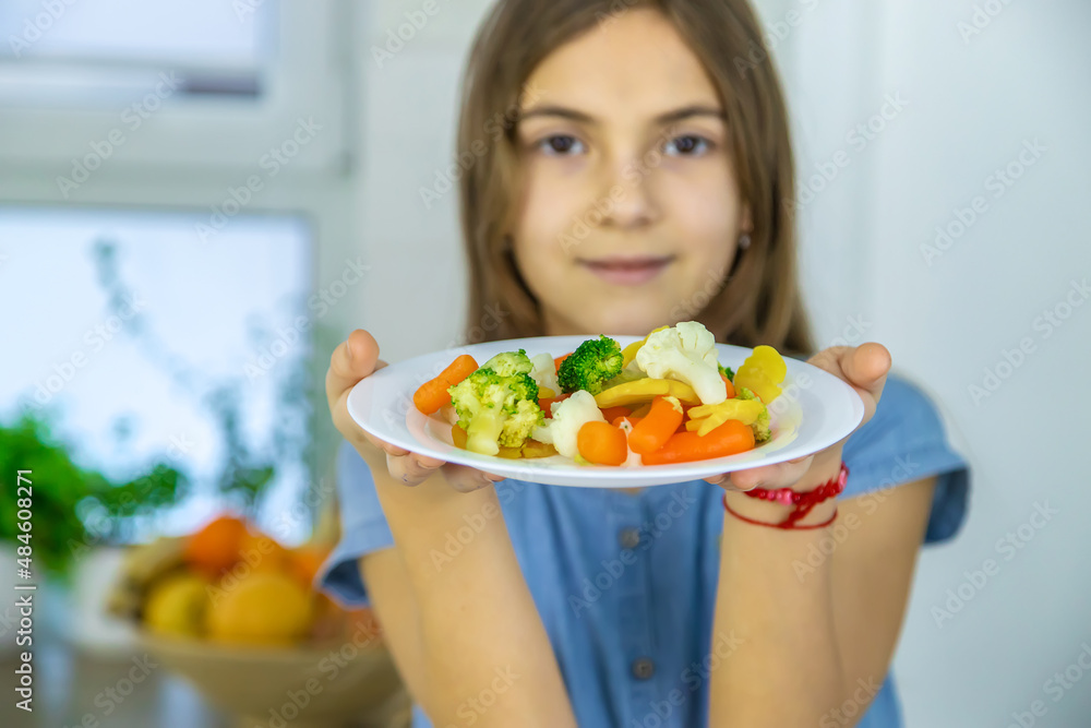 The child eats vegetables on a chair. Selective focus. The child eats vegetables on a chair. Selective focus.