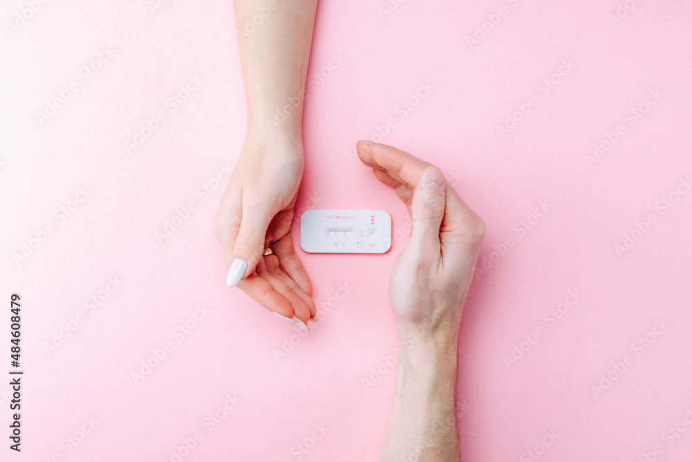 Pregnancy test kit. Female hand hold positive pregnant test with silk ribbon on pink banner