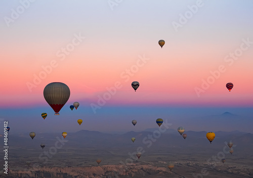 Hot air balloons in the sky during sunrise. Flying over the valley at Cappadocia, Anatolia, Turkey. Volcanic mountains in Goreme national park.