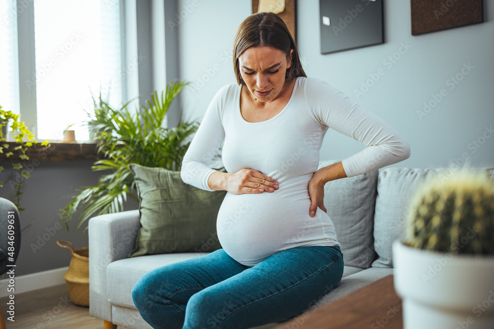 The woman feels stomach pain while working in the office, her hands