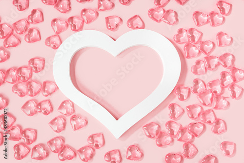 St Valentines day pink background banner. Many glass hearts around white heart frame flat lay. Love or wedding concept