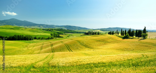 Stunning view of fields and farmlands with small villages on the horizon. Summer rural landscape of rolling hills, curved roads and cypresses of Tuscany, Italy. © MNStudio