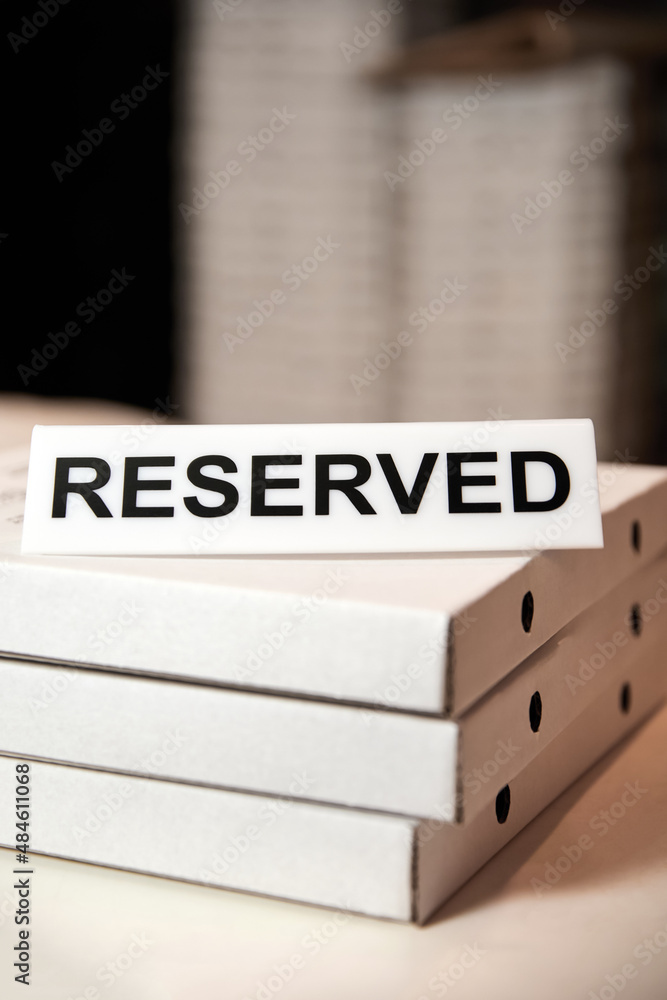 Plastic plaque with the inscription Reserved on the closed boxes with pizza Plastic plaque with the inscription Reserved on the closed boxes with pizza