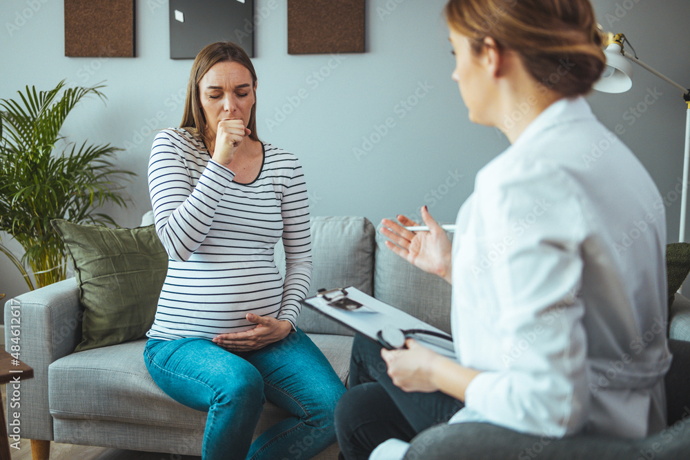 Young pregnant woman talking with doctor. Pregnant Woman Coughing. Woman during a routine check