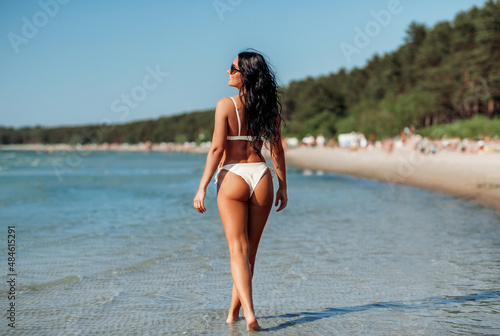 people, summer and swimwear concept - happy smiling young woman in bikini swimsuit on beach