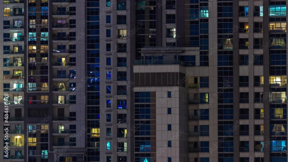 Apartment windows of a glazed skyscraper glow at night with city lights reflection aerial timelapse. Apartment windows of a glazed skyscraper glow at night with city lights reflection aerial timelapse.