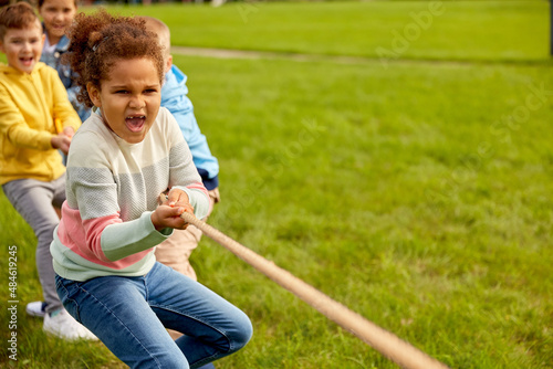 Foto childhood, leisure and people concept - group of happy kids playing tug-of-war g