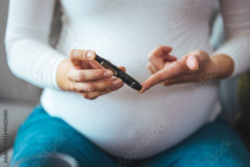 A pregnant woman hands using lancet on finger to check blood sugar test level by Glucose meter  Healthcare Medical and Check up  Medicine  diabetes  glycemia  health care and people concept